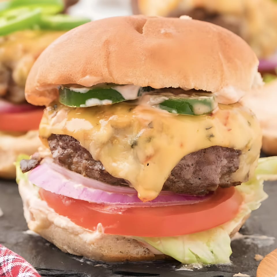 A NY Style Delicatessen burger with melted cheese, jalapenos, red onion, tomato, and lettuce.